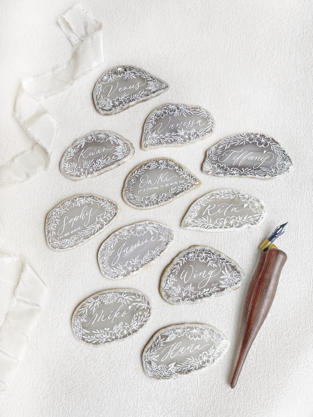 Agate slice place cards lettered in gold calligraphy beside a pointed pen