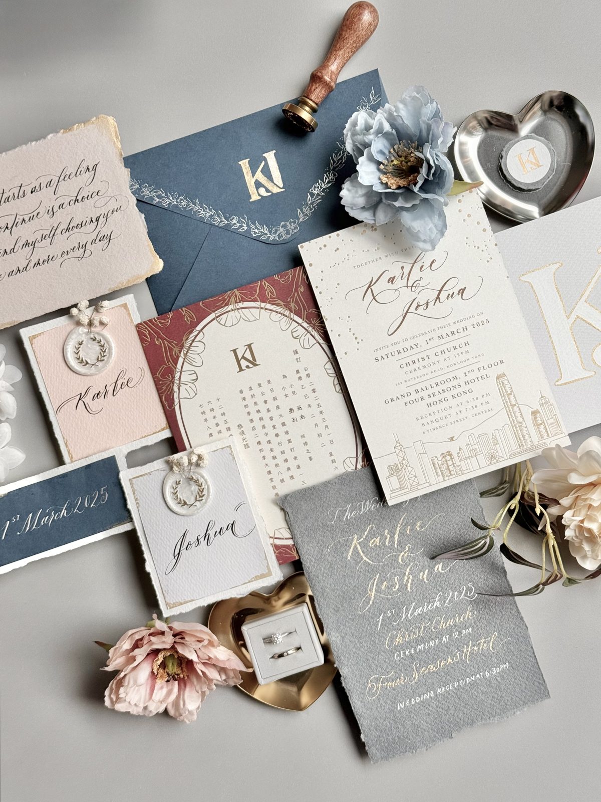 Navy and blush wedding invitation flat lay with calligraphed details cards and brass seal