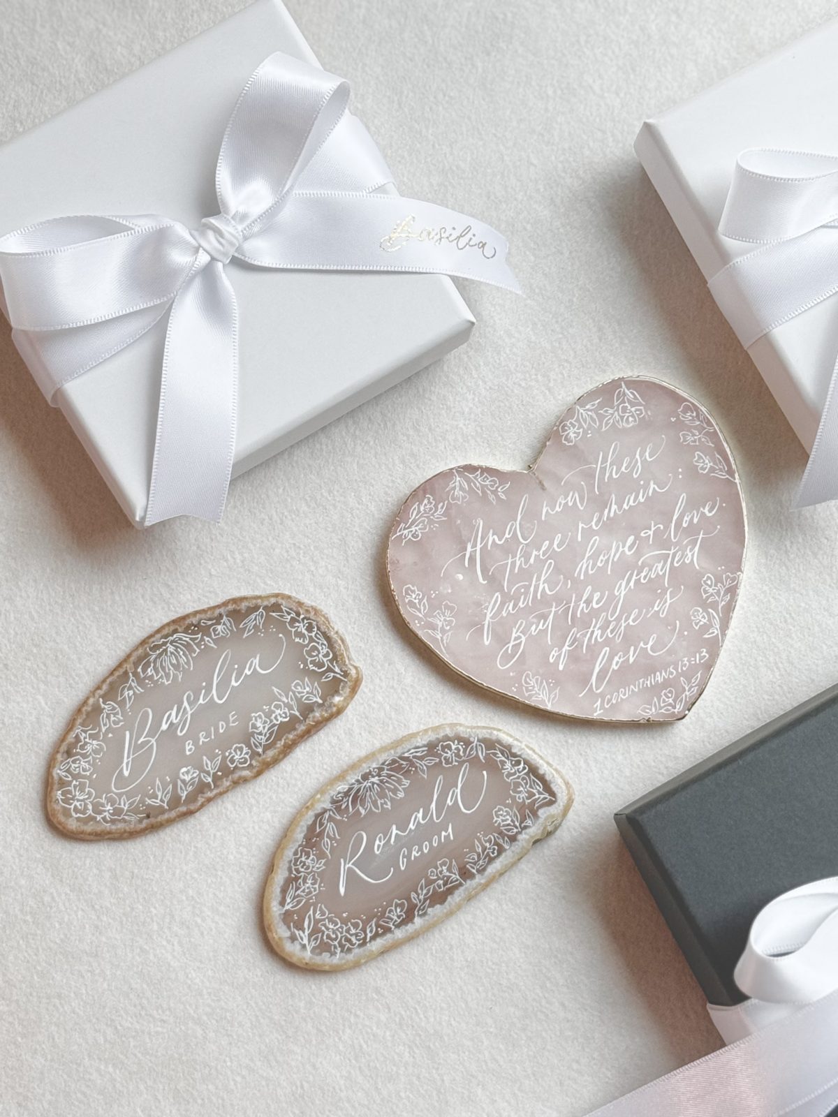 Agate slice keepsakes with gold calligraphy beside a white ribboned gift box