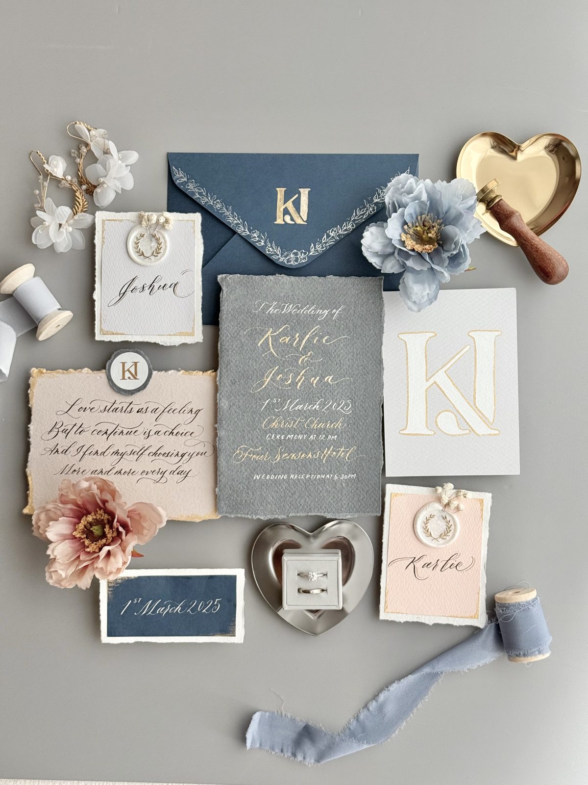 Styled wedding stationery flat lay with monogram envelope, ribbon and gold seals