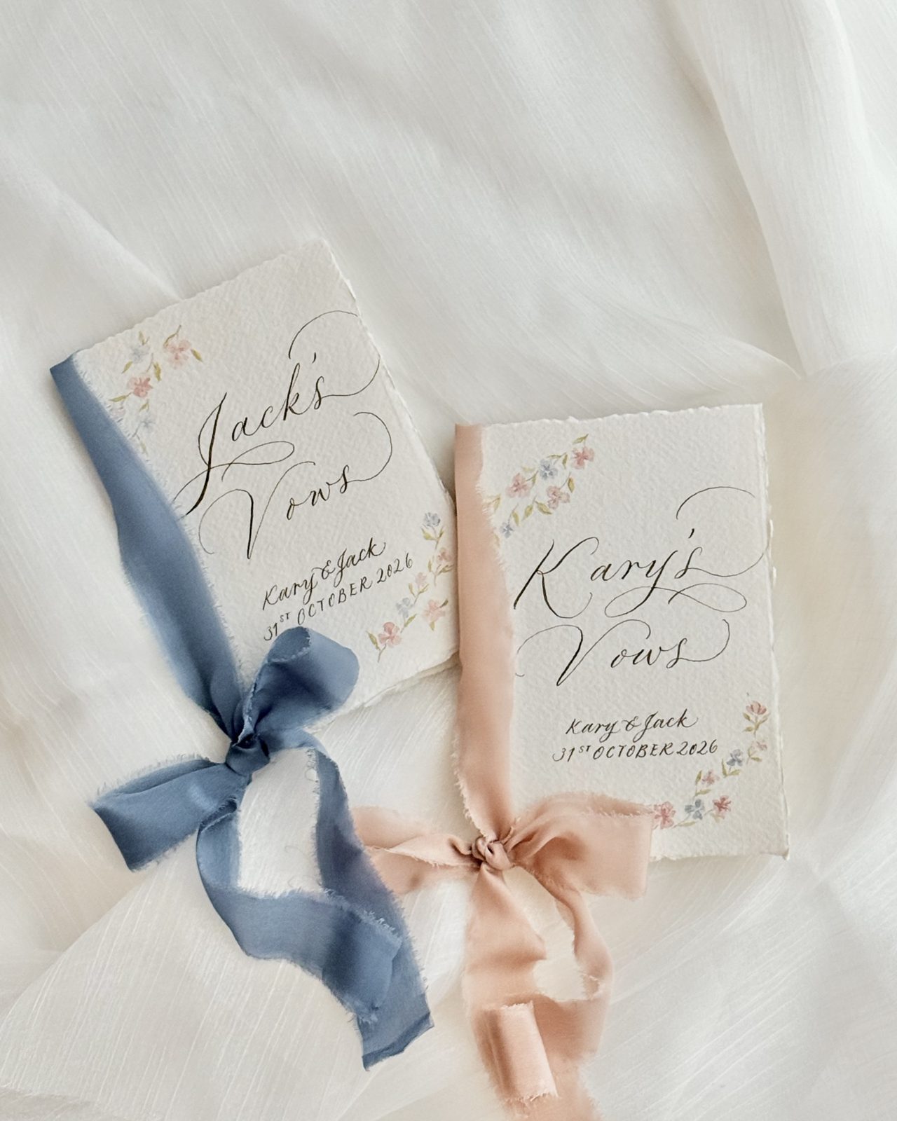 Pair of hand calligraphed vow books tied with dusty blue and blush silk ribbon