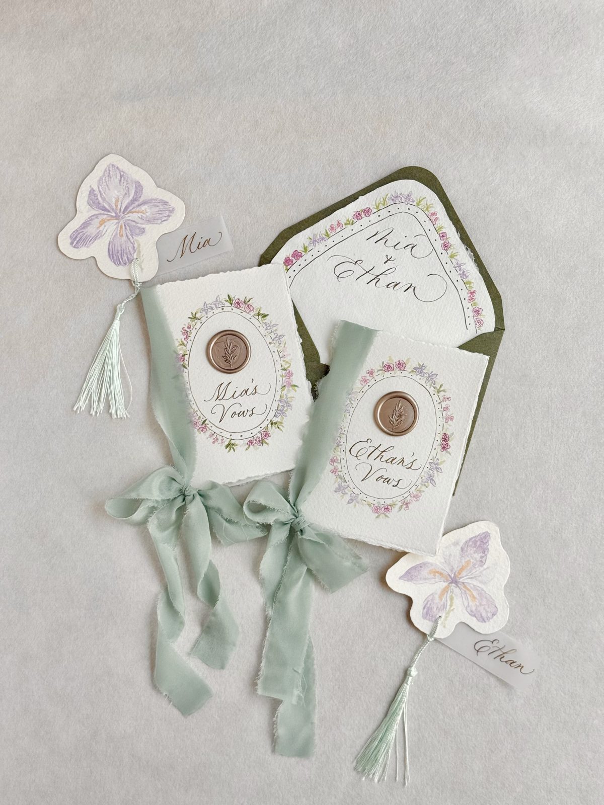 Vow books with sage ribbon and pressed floral wedding stationery details