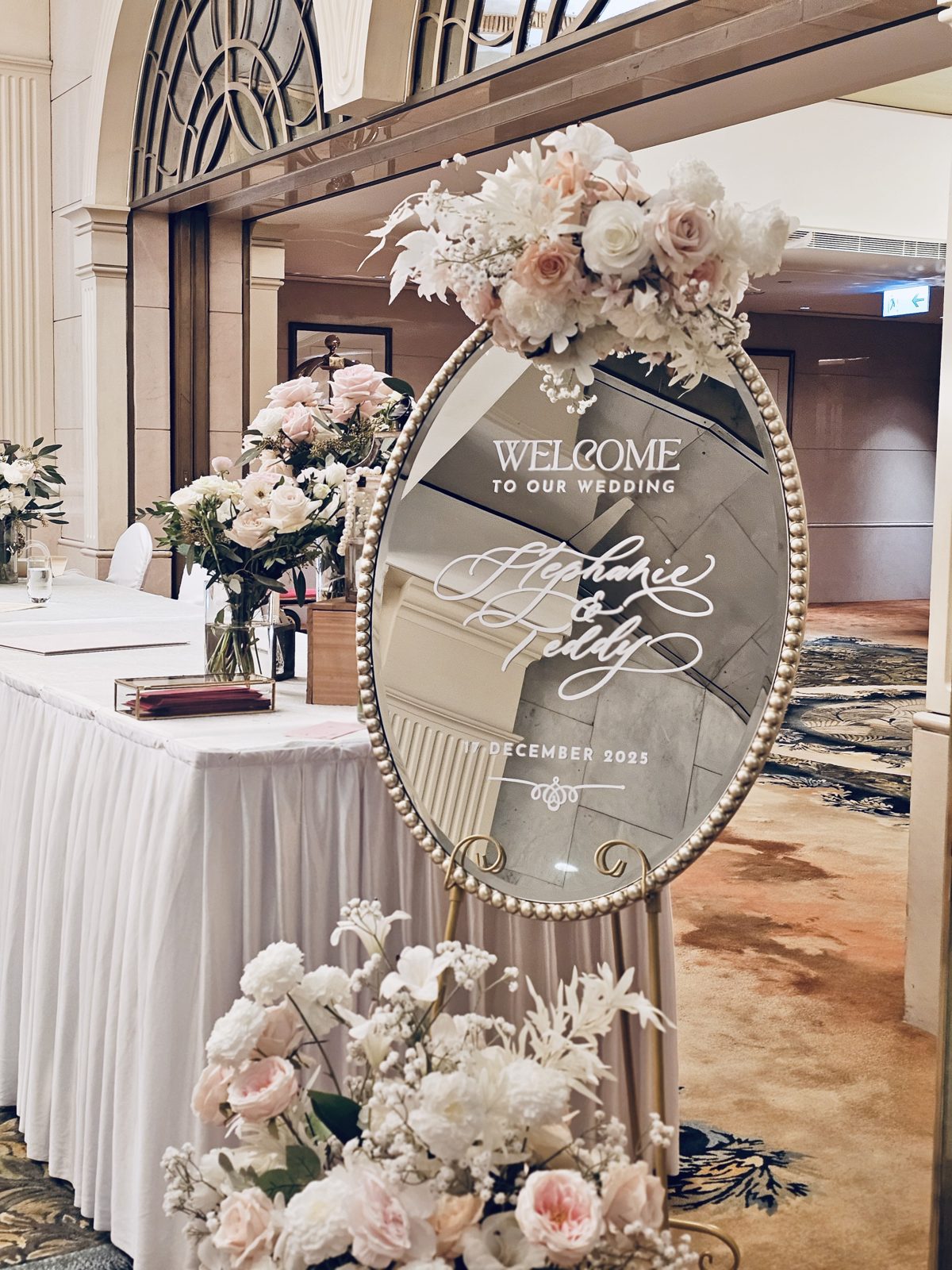 Mirrored wedding welcome sign in calligraphy framed by a floral arrangement in a Hong Kong ballroom