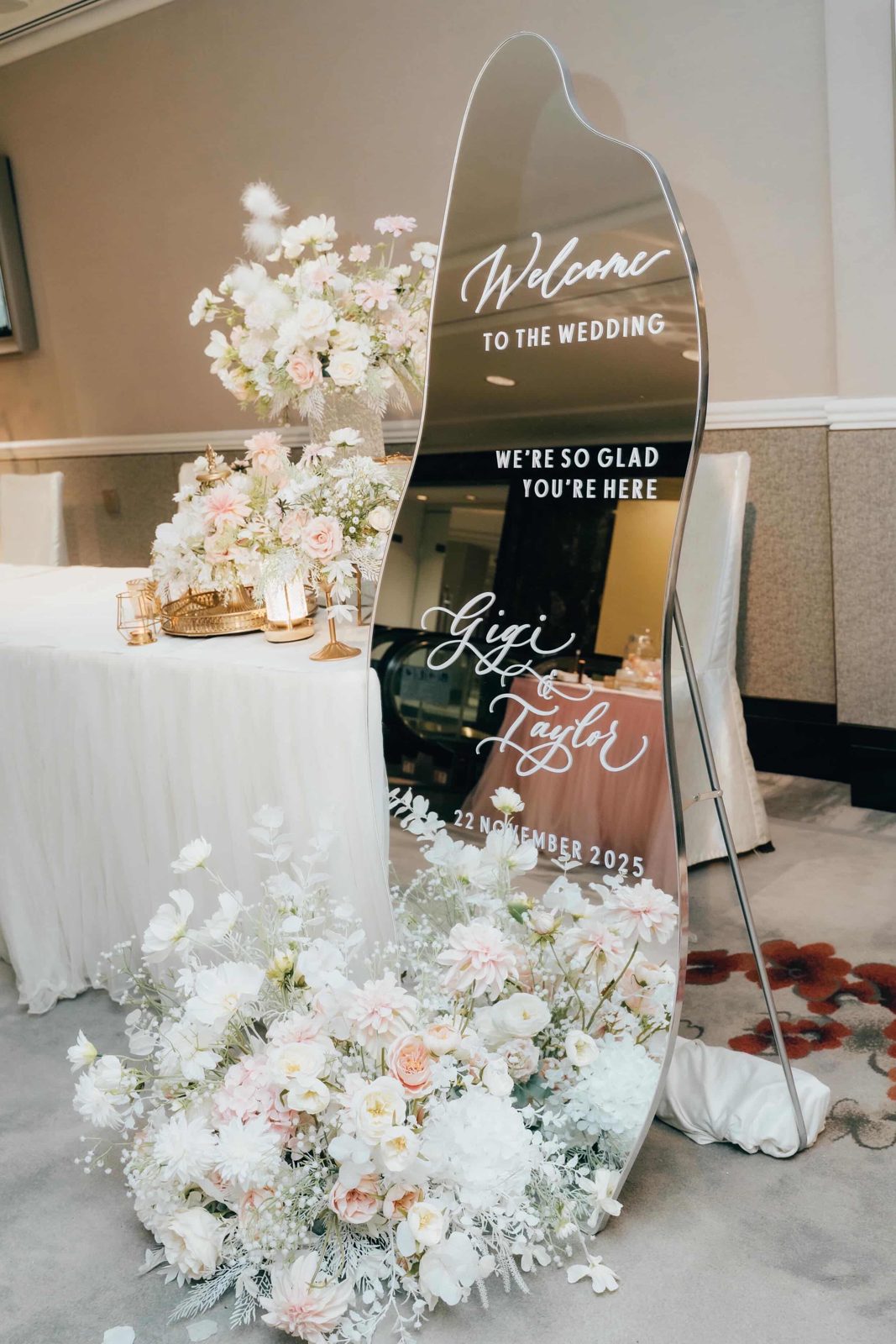 Wedding welcome signage with calligraphed couple names above a white floral installation