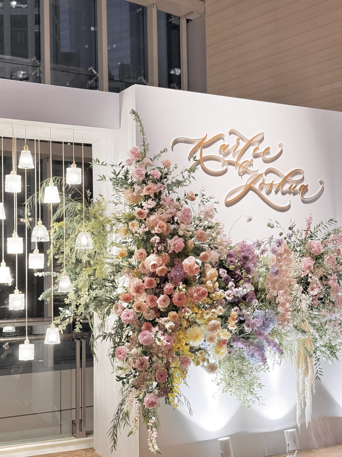 Illuminated wedding backdrop with calligraphed couple names and blossom florals